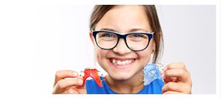 Young girl holding two retainers